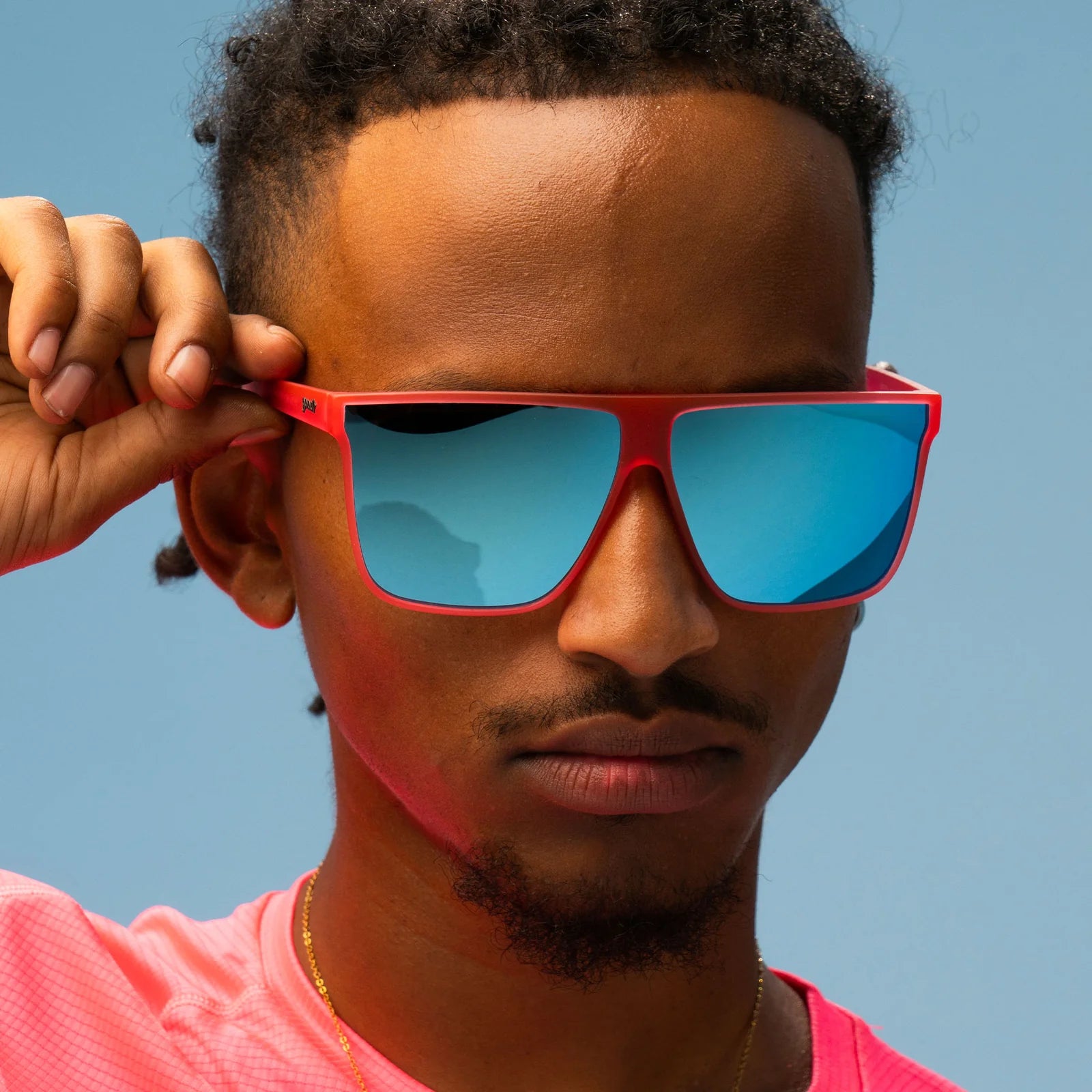 Style and fit showcase of hot pink translucent frames with teal reflective lenses. Wider-fit, flat-top sunglasses.