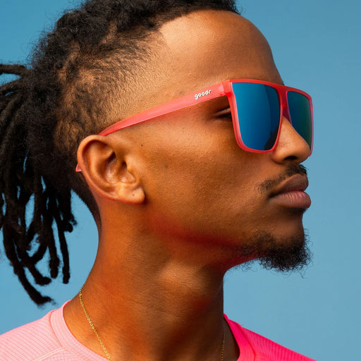 Style and fit showcase of hot pink translucent frames with teal reflective lenses. Wider-fit, flat-top sunglasses
